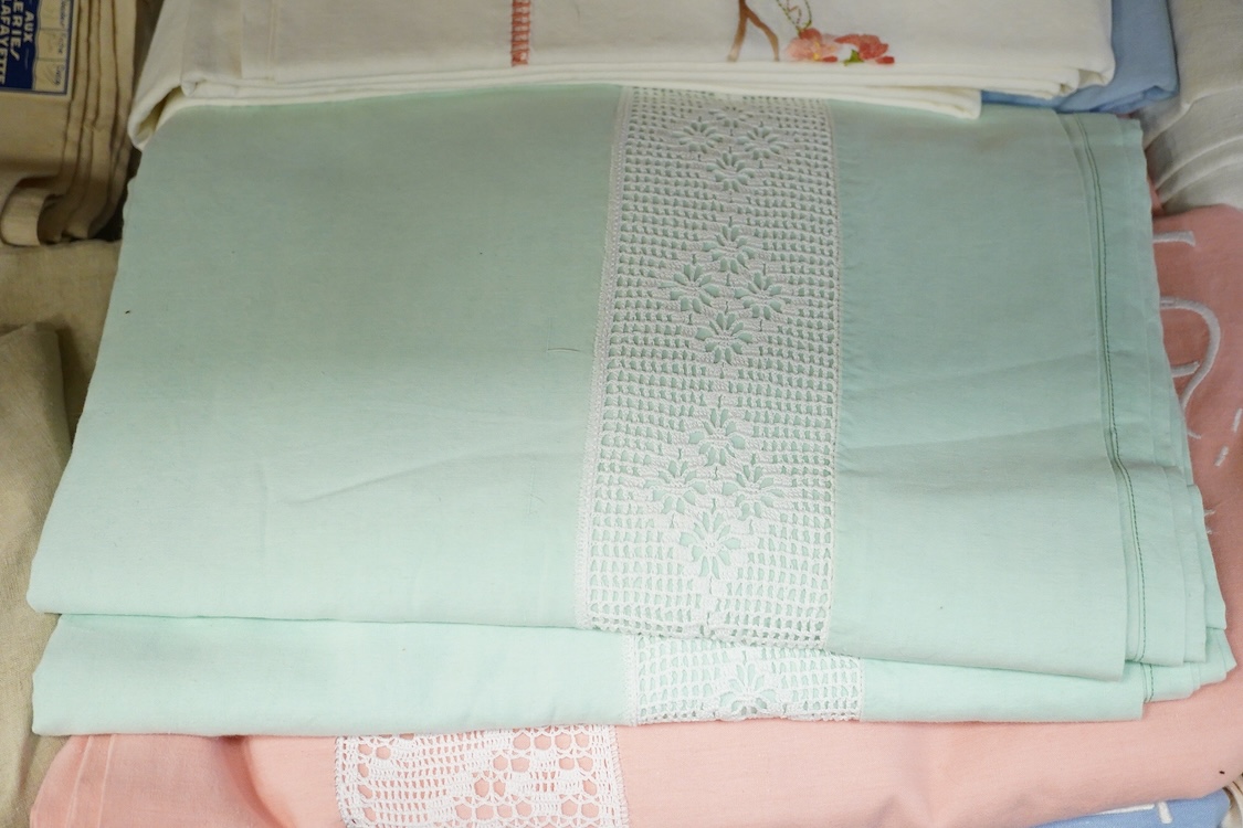 Thirteen mixed French mostly coloured provincial linen sheets some embroidered with monograms, floral embroidery, or decorated with crochet.
